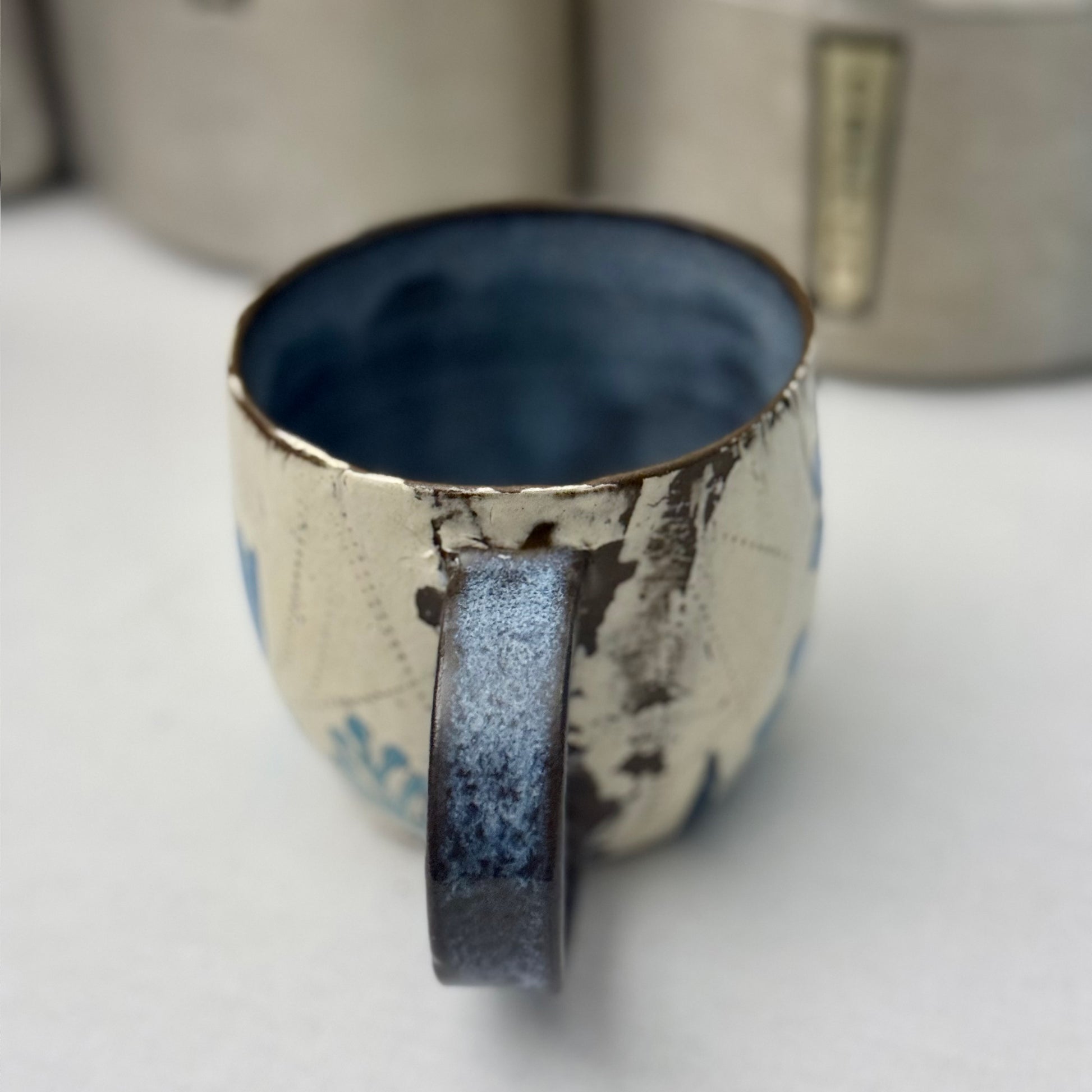 Ceramic mug with blue  and green floral design on a white surface