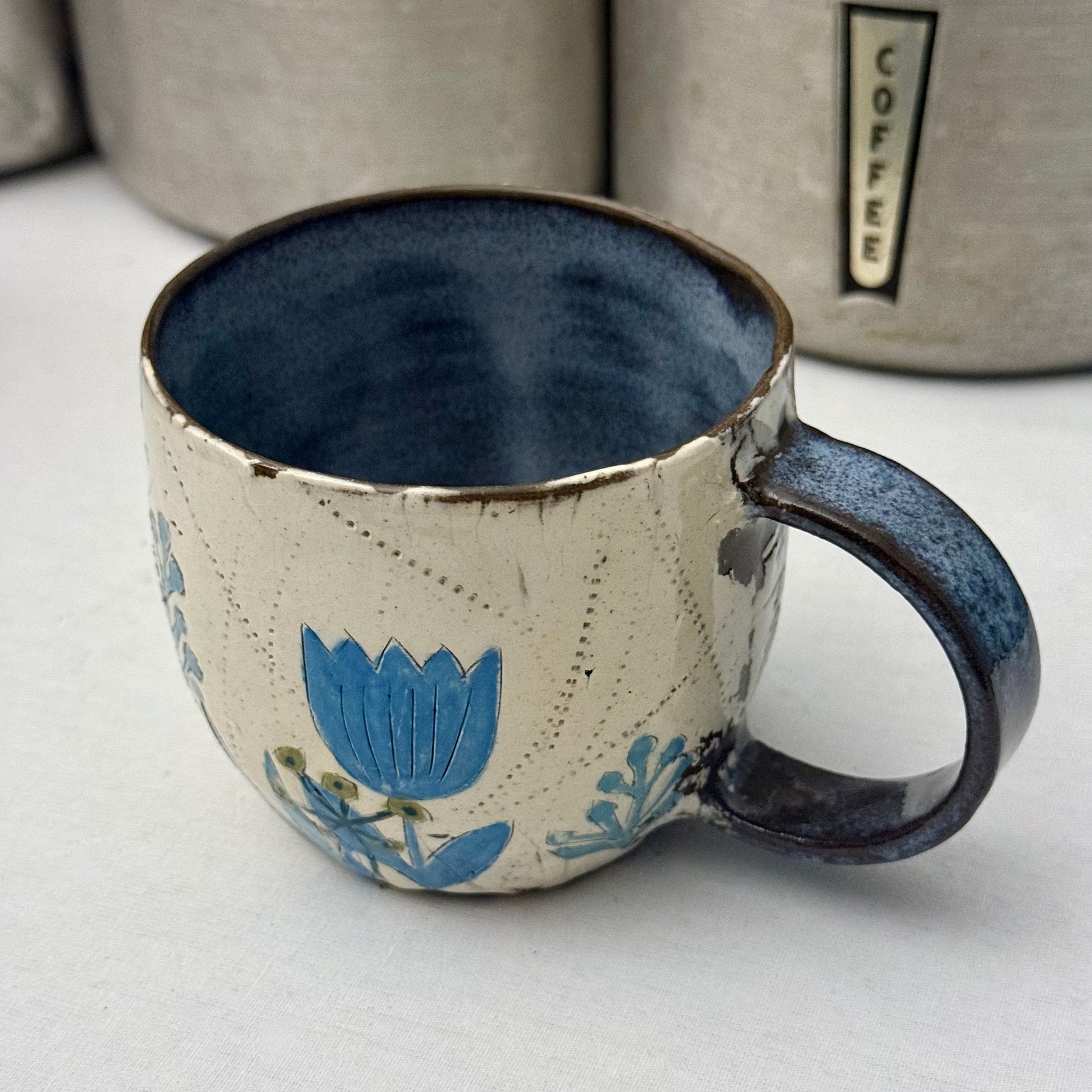 Ceramic mug with blue  and green floral design on a white surface