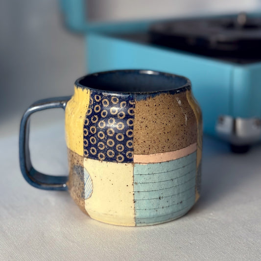 Multicolored ceramic mug with a textured design on a neutral background