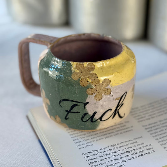 Multicolored Floral fuck mug sitting on a book.