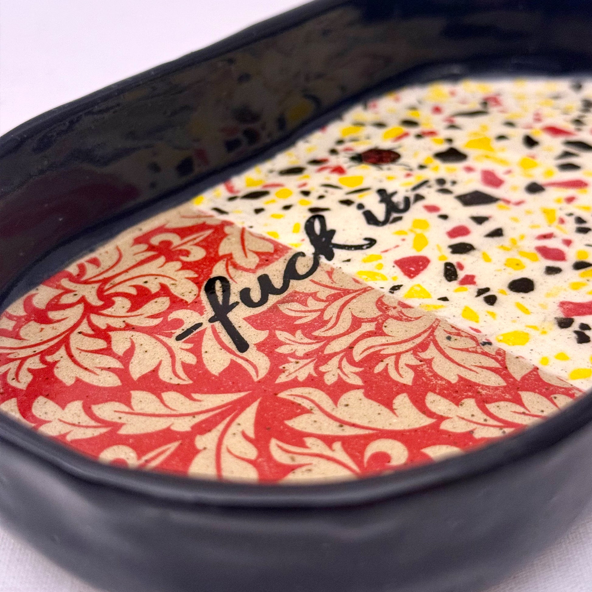 Decorative tray with damask pattern, black text, lady bug, and terrazzo design on a white background