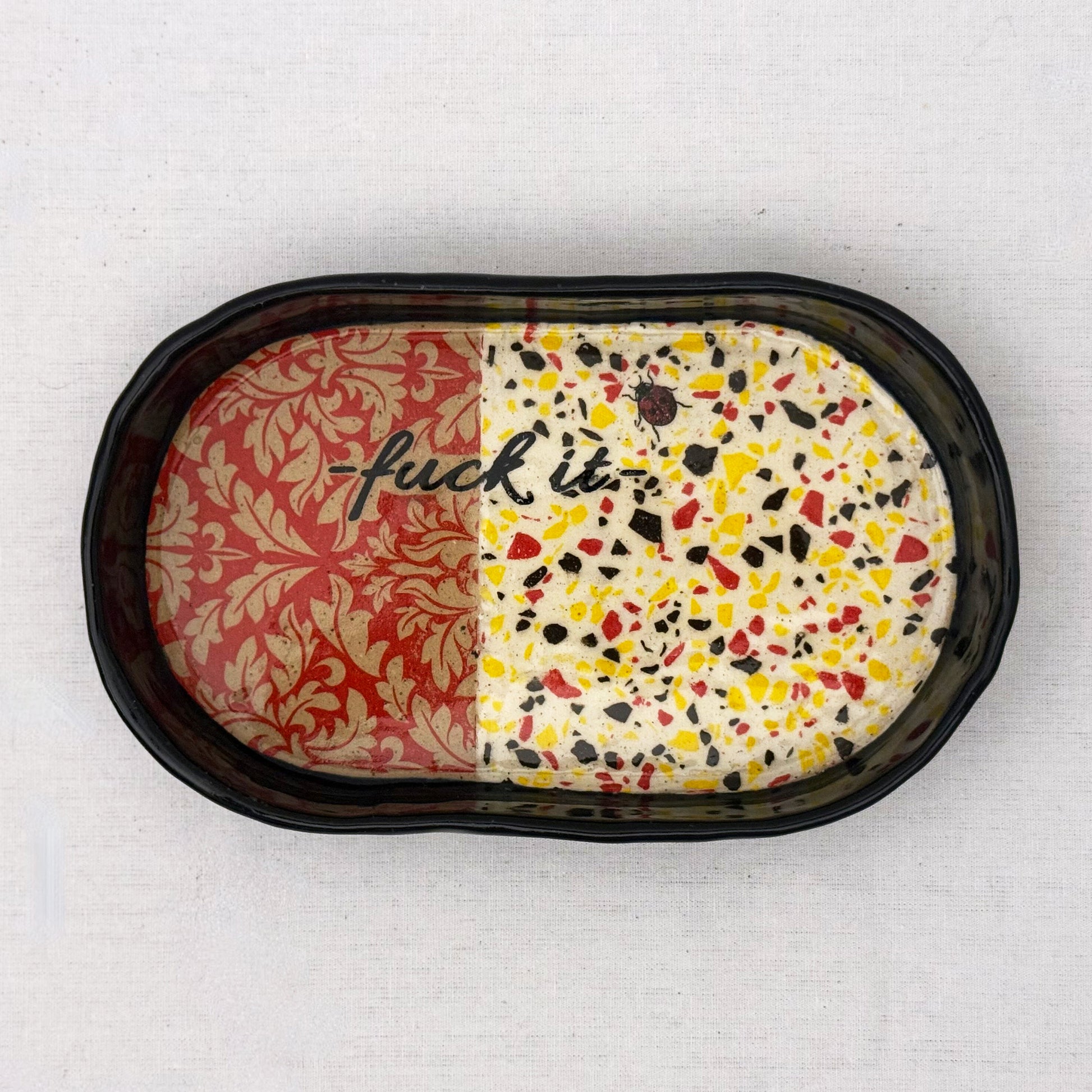 Decorative tray with damask pattern, black text, lady bug, and terrazzo design on a white background