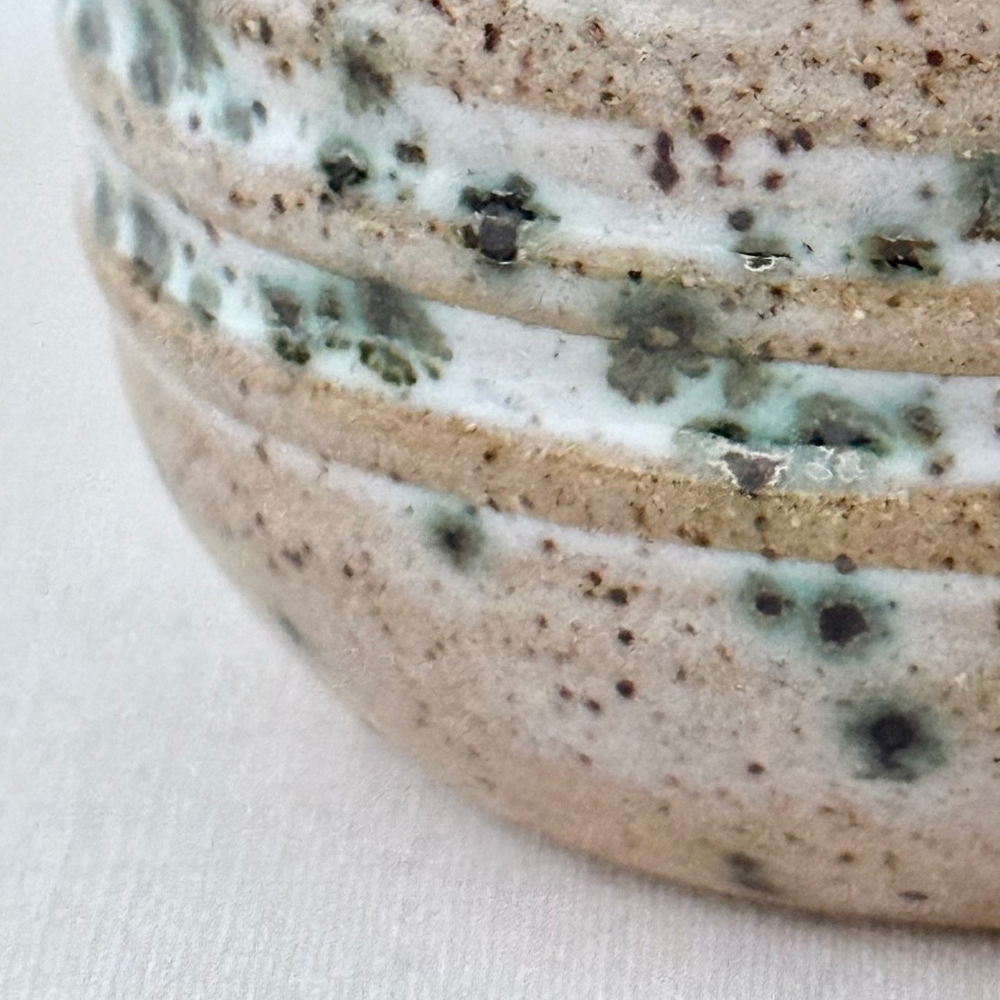 Close-up of a ceramic bowl with speckled glaze on a white background