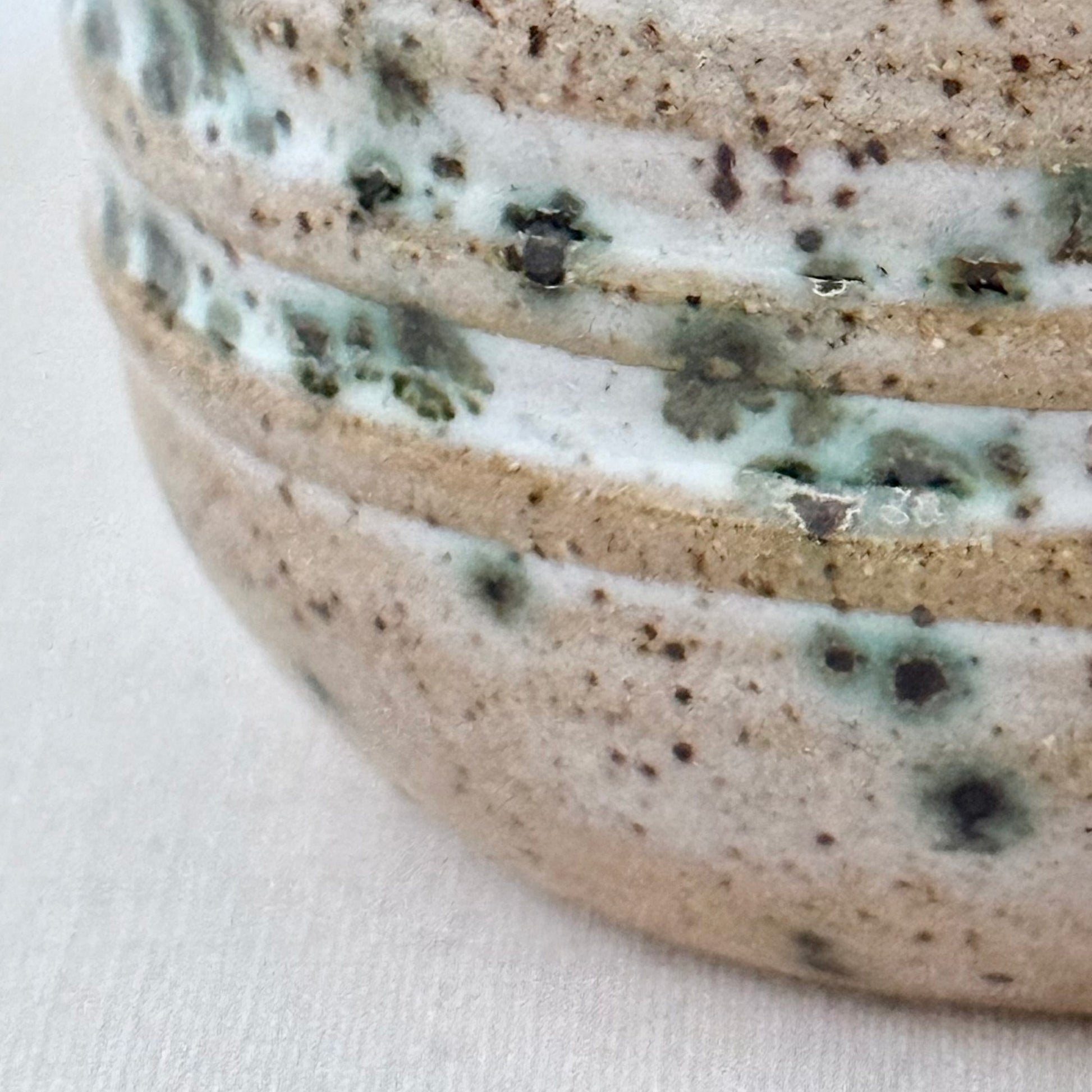 Close-up of a ceramic bowl with speckled glaze on a white background