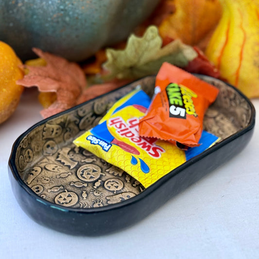 Halloween-themed candy dish with candy bars on a white surface