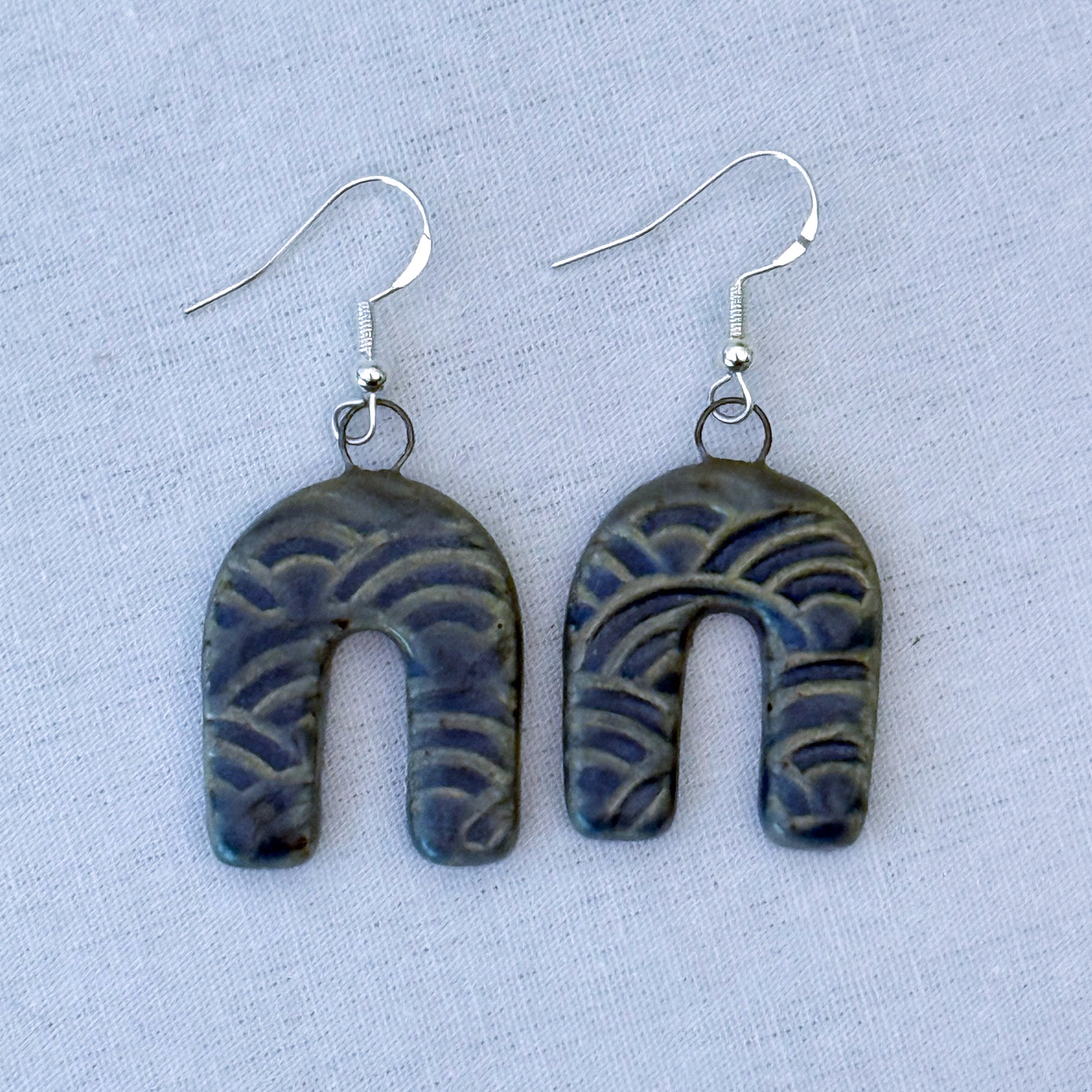 Pair of blue patterned earrings on a light blue background
