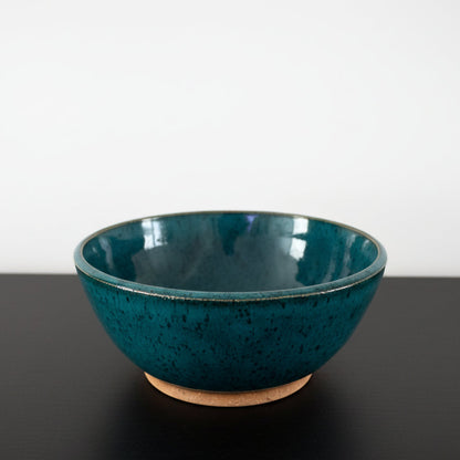 A handmade ceramic bowl with a teal glaze