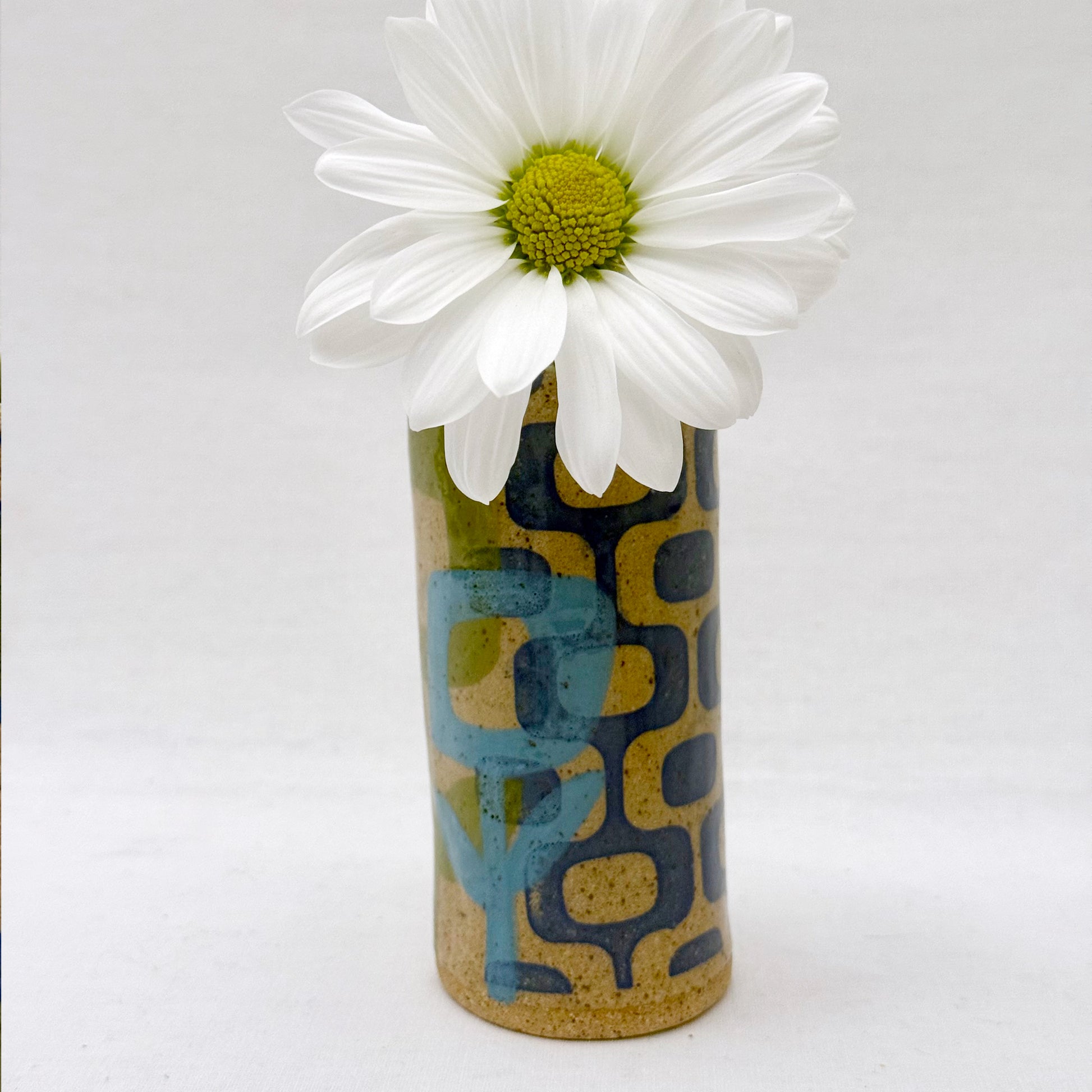 Decorative vase with a geometric pattern and a white flower on a white background