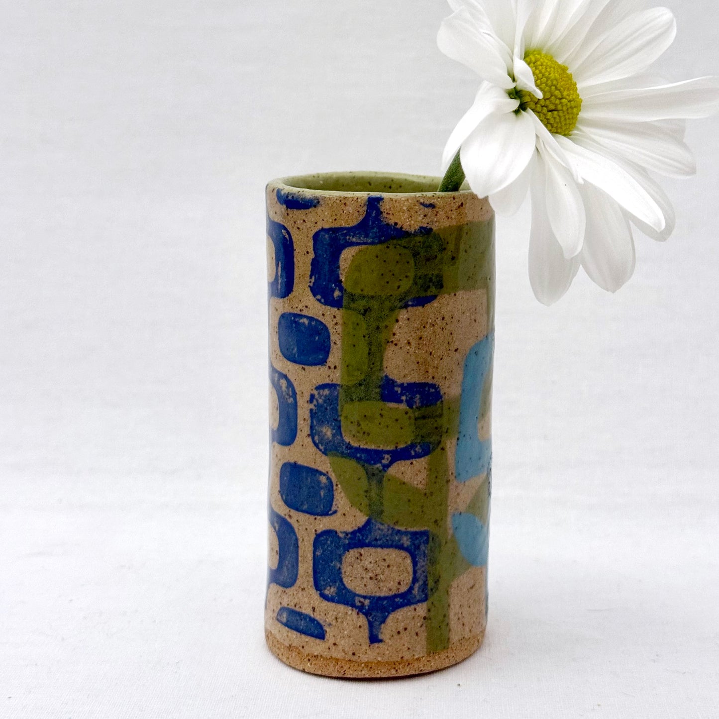Ceramic vase with geometric pattern and white flower on a white background
