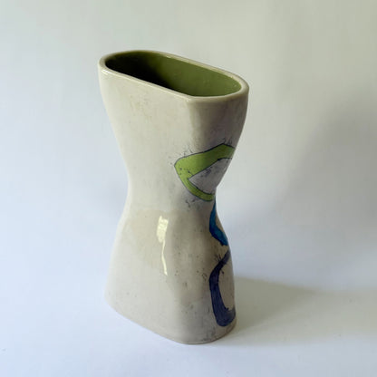 Handmade ceramic vase with interconnected geometric shapes in blue, coral, green, and gray on a sculptural hourglass silhouette.
