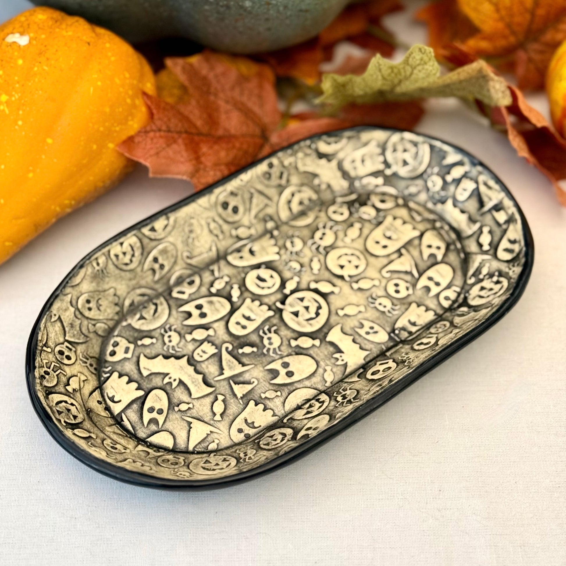 Halloween themed oval plate on light background with leaves and pumpkins