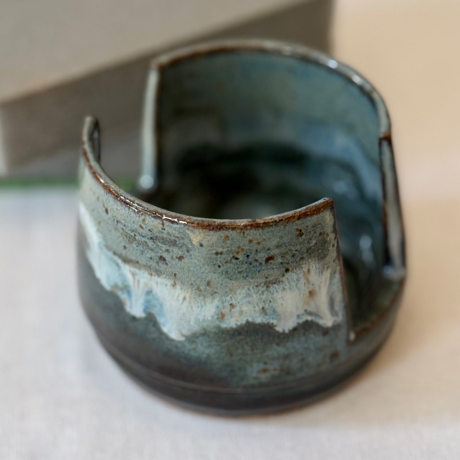Ceramic sponge holder with blue and brown glaze on a neutral background