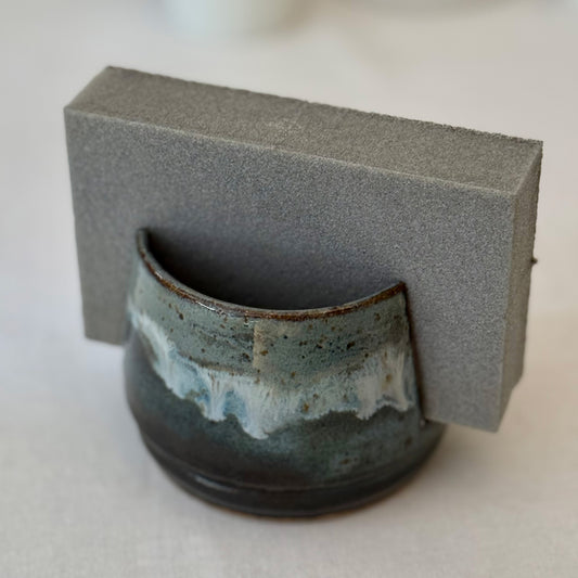 Ceramic sponge holder with blue and brown glaze on a neutral background