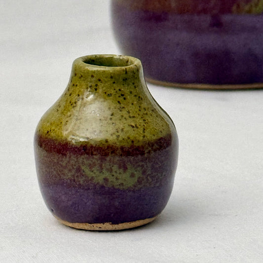 Small ceramic vase with purple and green glaze on a white background