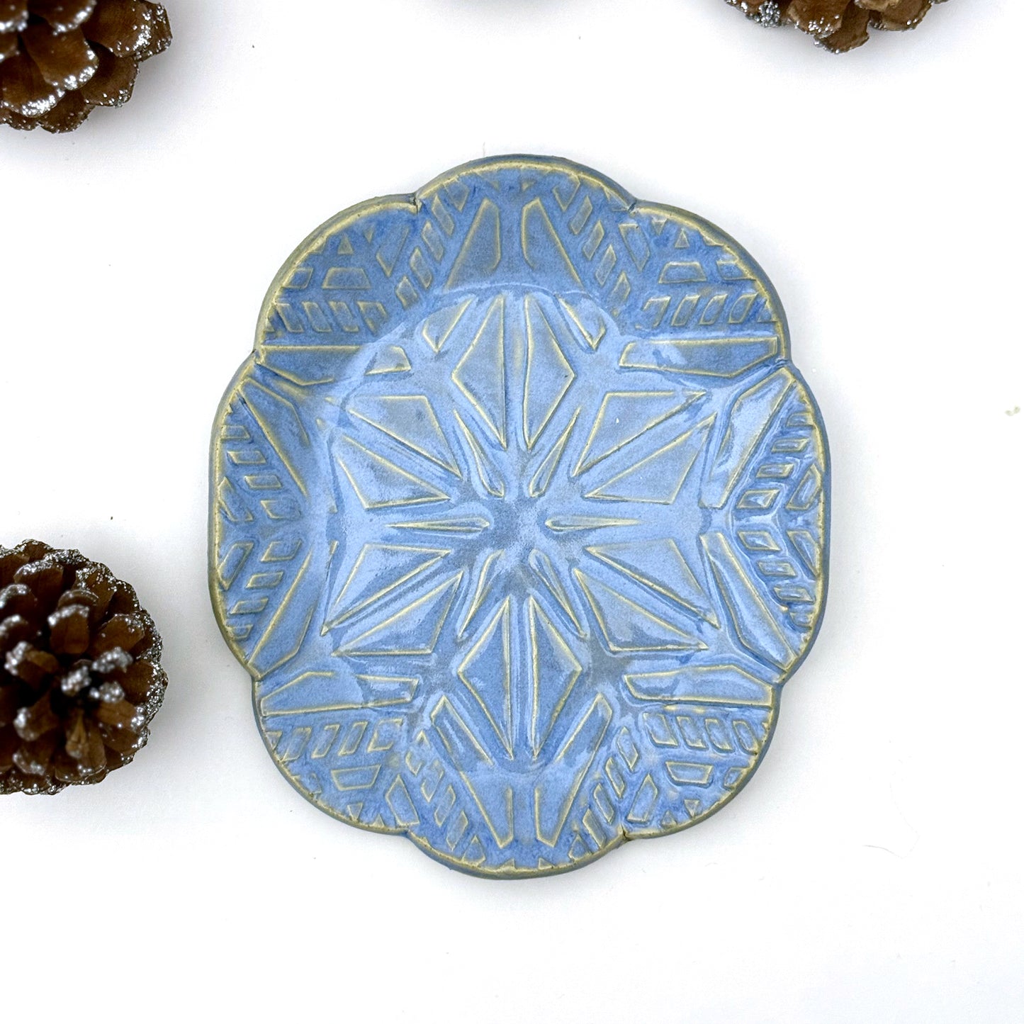 Blue ceramic plate with geometric snowflake pattern on a white background
