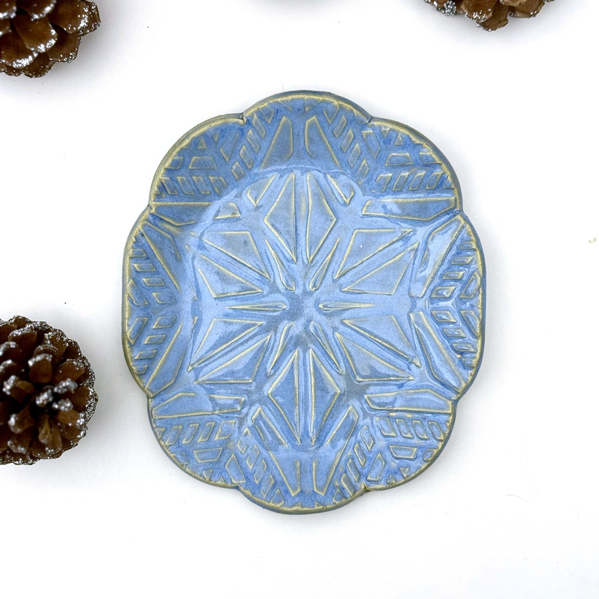 Blue ceramic plate with geometric snowflake pattern on a white background