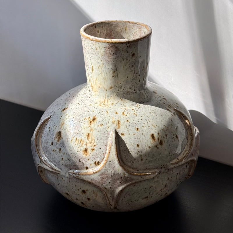 Handcrafted ceramic bud vase with a carved mid-century modern starburst pattern and warm speckled ivory glaze.