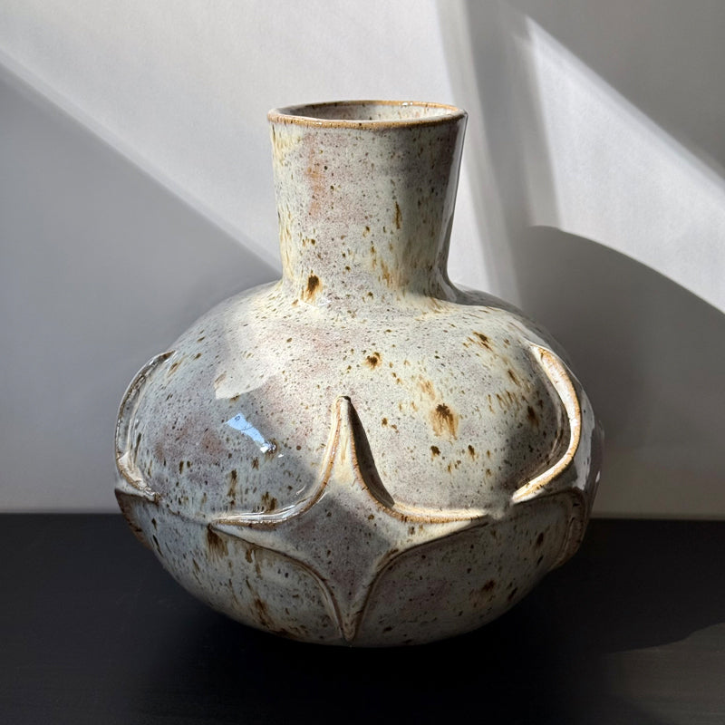 Handcrafted ceramic bud vase with a carved mid-century modern starburst pattern and warm speckled ivory glaze.