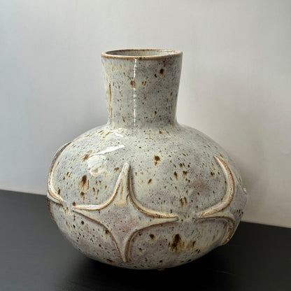 Handcrafted ceramic bud vase with a carved mid-century modern starburst pattern and warm speckled ivory glaze.