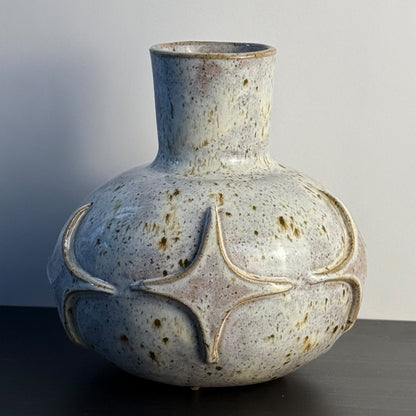 Handcrafted ceramic bud vase with a carved mid-century modern starburst pattern and warm speckled ivory glaze.