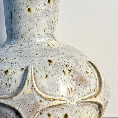 Close up of andcrafted ceramic bud vase with a carved mid-century modern starburst pattern and warm speckled ivory glaze.