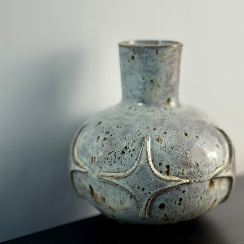 Handcrafted ceramic bud vase with a carved mid-century modern starburst pattern and warm speckled ivory glaze.