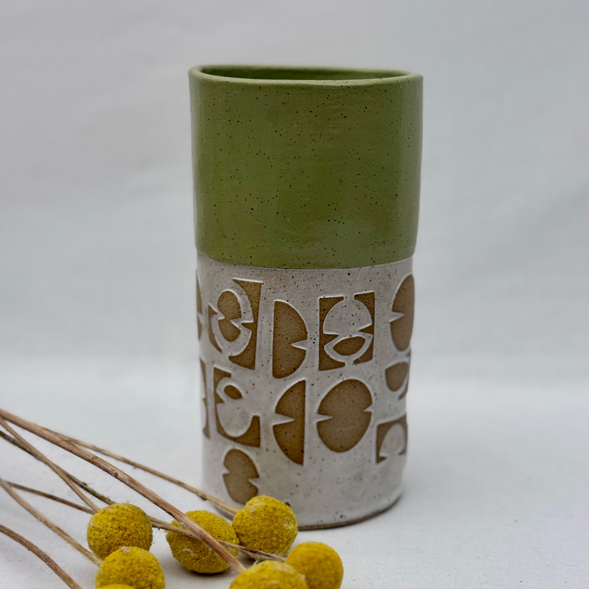 Green ceramic vase with decorative patterns on a white background