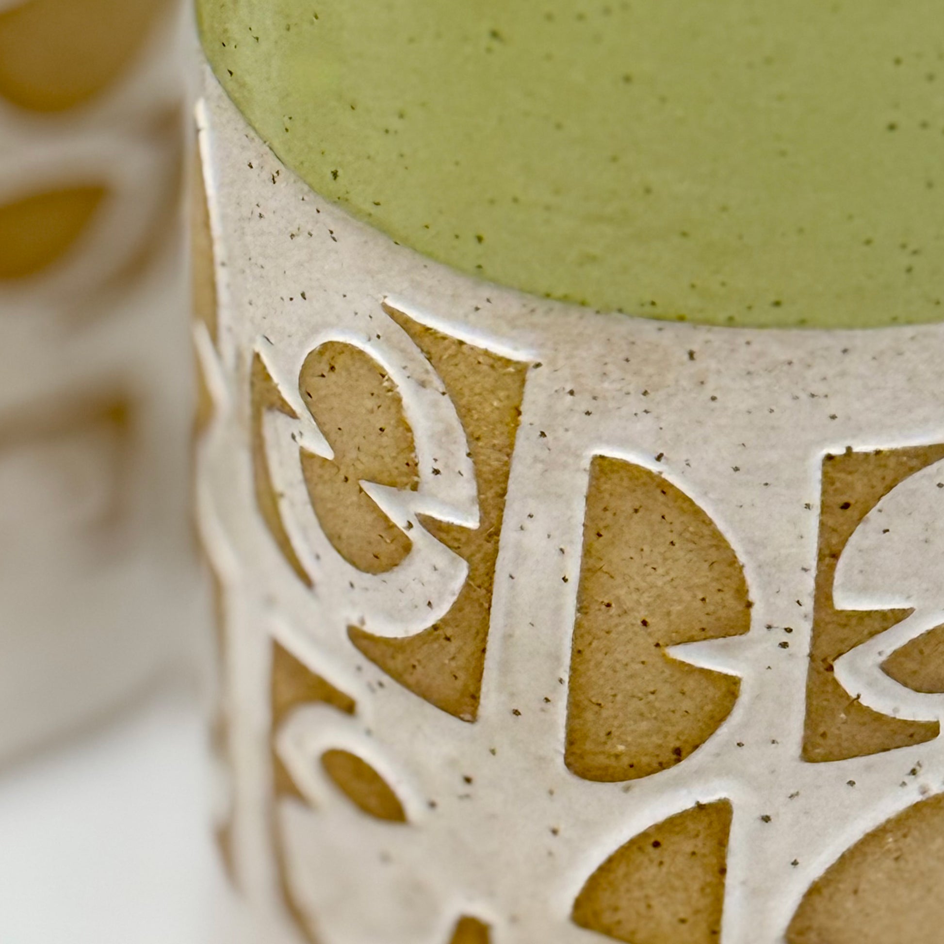 Close-up of a ceramic vase with decorative cut-out patterns on a white background