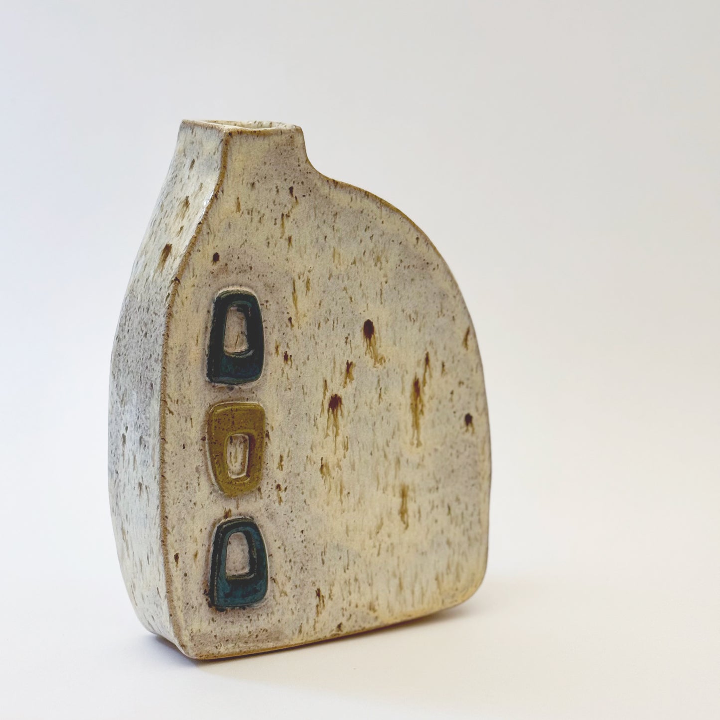 Mid-century modern ceramic vase with three raised turquoise and olive green geometric shapes on a speckled cream stoneware body.