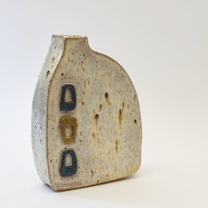 Mid-century modern ceramic vase with three raised turquoise and olive green geometric shapes on a speckled cream stoneware body.