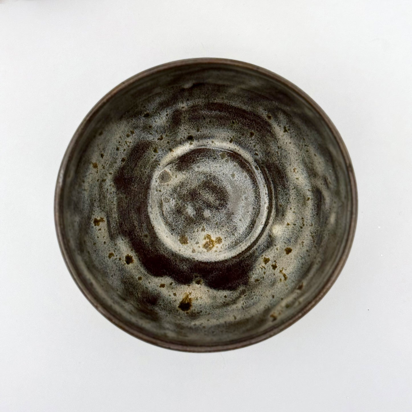 top view of black stoneware bowl with beige glaze a white background