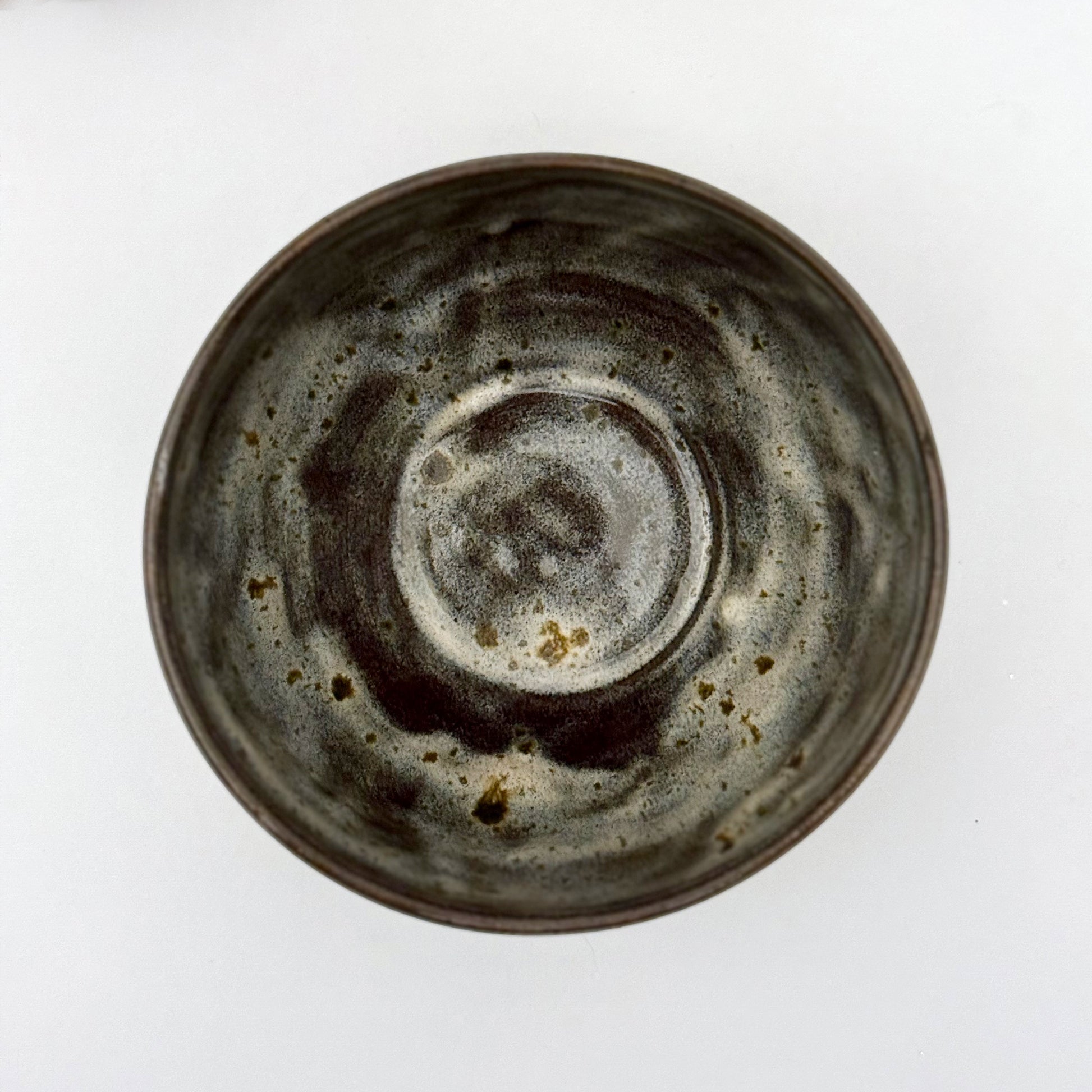 top view of black stoneware bowl with beige glaze a white background