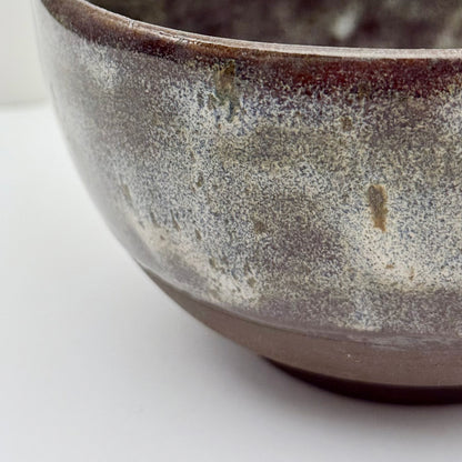 Close-up of black stoneware bowl with beige glaze a white background