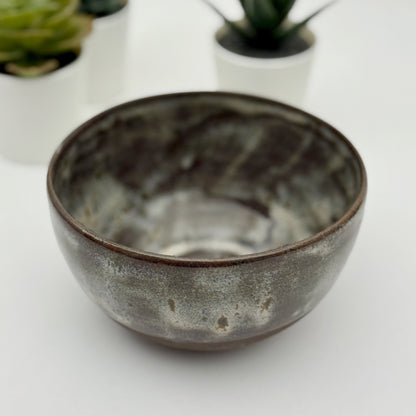 black stoneware bowl with beige glaze a white background