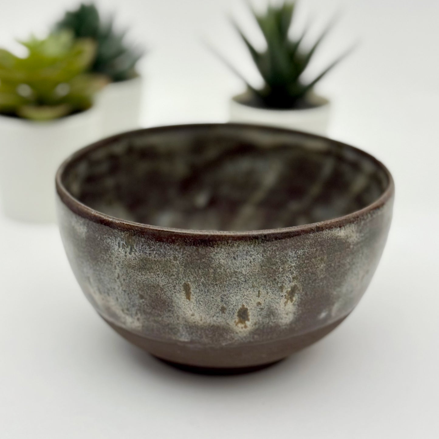 black stoneware bowl with beige glaze a white background