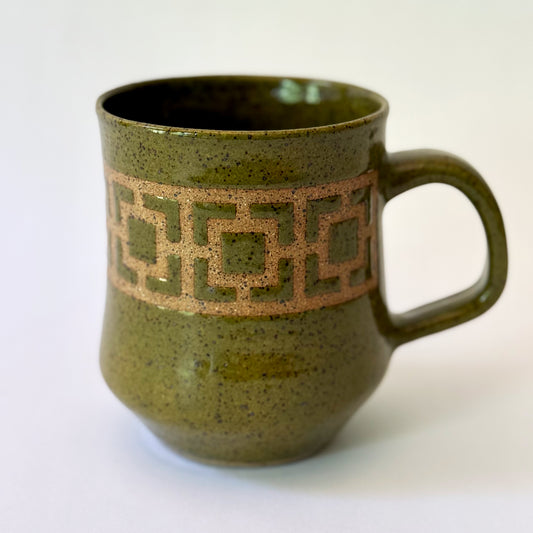 Glossy olive-green speckled mug featuring a contrasting mid-century geometric breeze block pattern.
