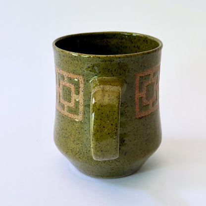 Glossy olive-green speckled mug featuring a contrasting mid-century geometric breeze block pattern.