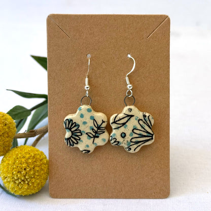Floral-patterned earrings on a brown card with yellow flowers in the background