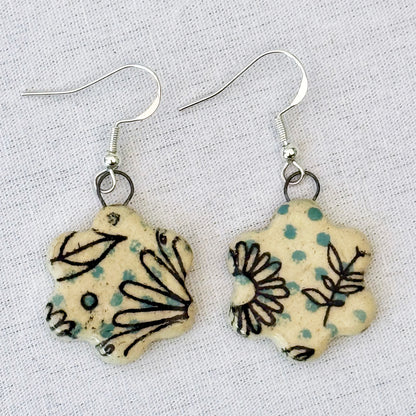 Pair of floral-patterned earrings on a light fabric background