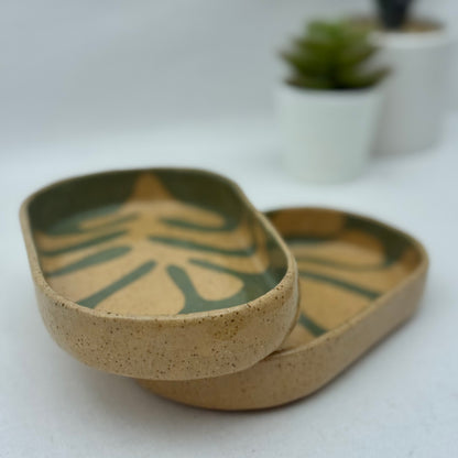 Two ceramic trays with leaf patterns on a white surface