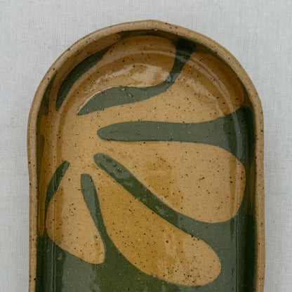 Ceramic dish with leaf design on a light gray background
