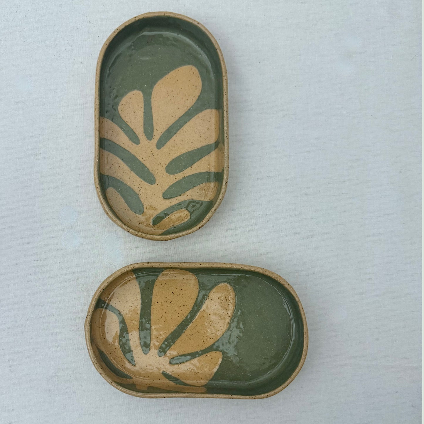 Two ceramic trays with leaf patterns on a light gray background