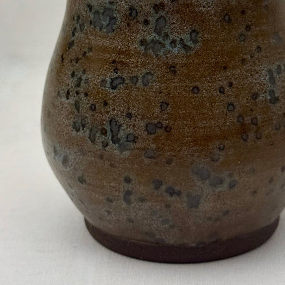 Close-up of a brown ceramic vase with speckled texture on a white background
