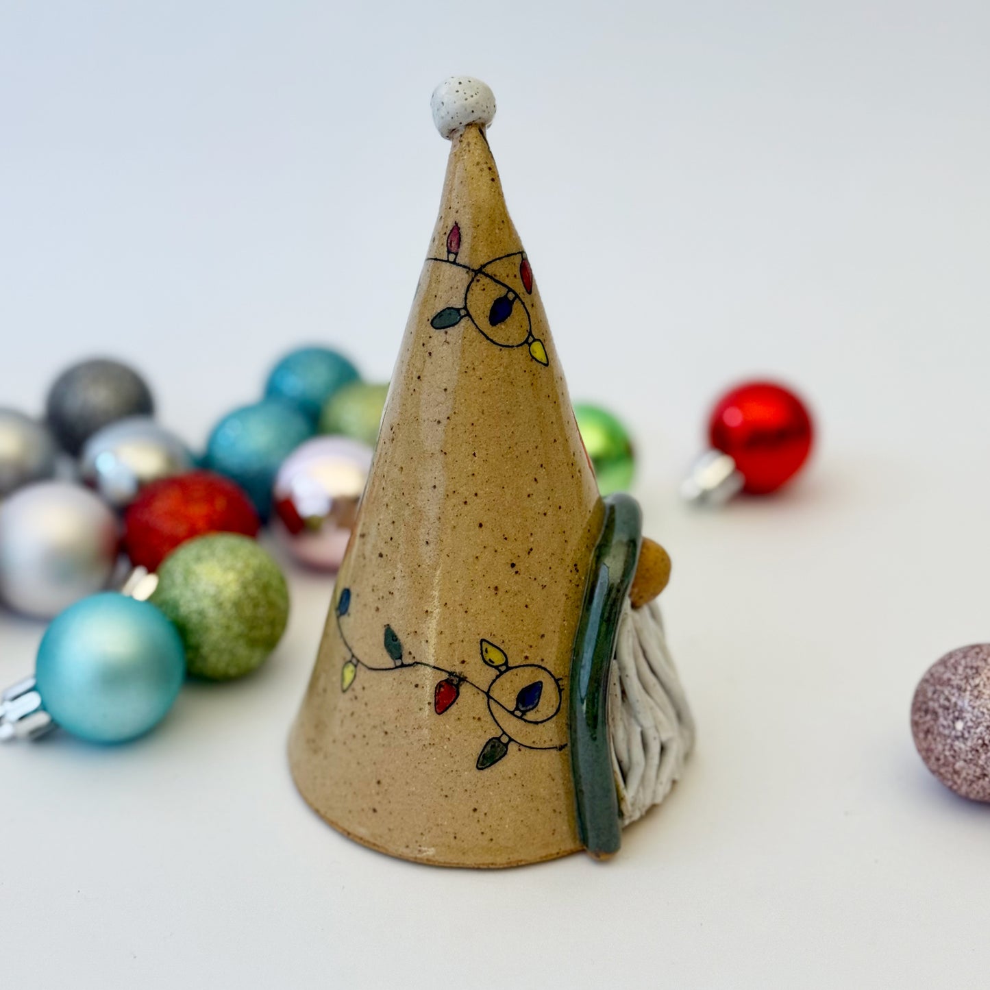 ceramic gnome with holiday lights with ornament on a white background