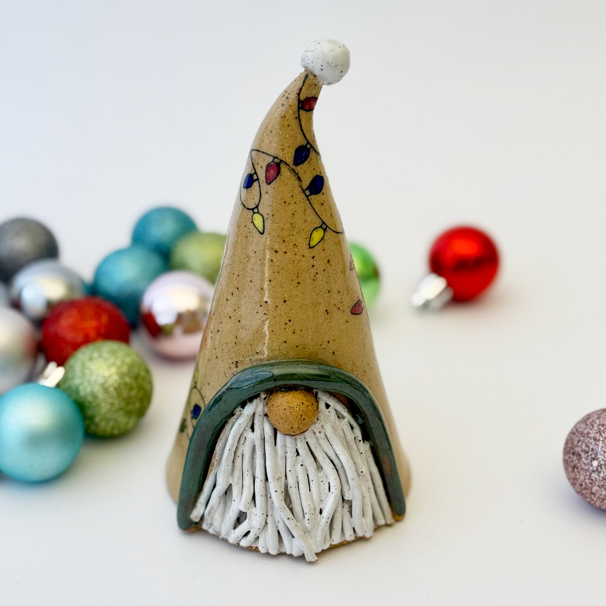 ceramic gnome with holiday lights with ornament on a white background