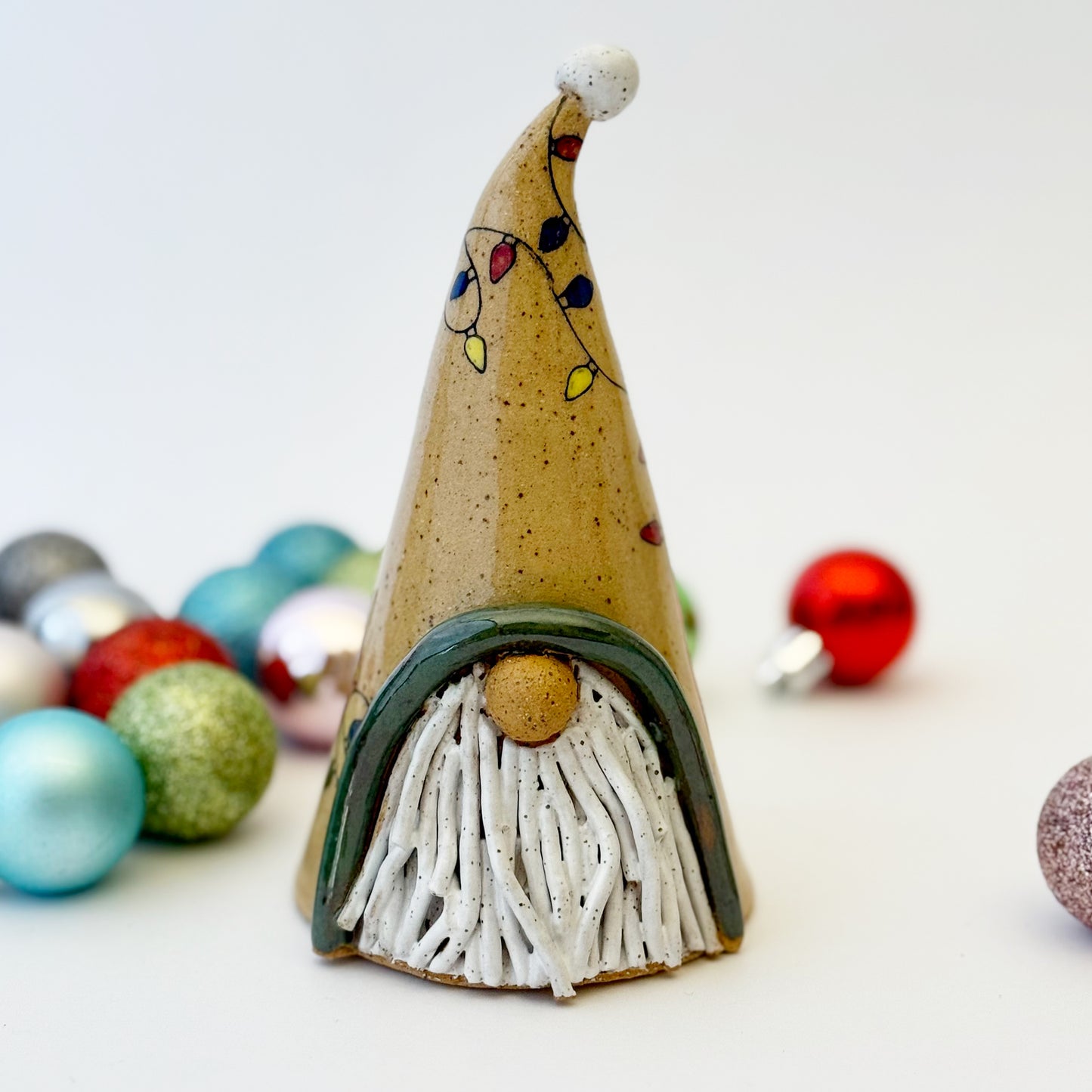ceramic gnome with holiday lights with ornament on a white background
