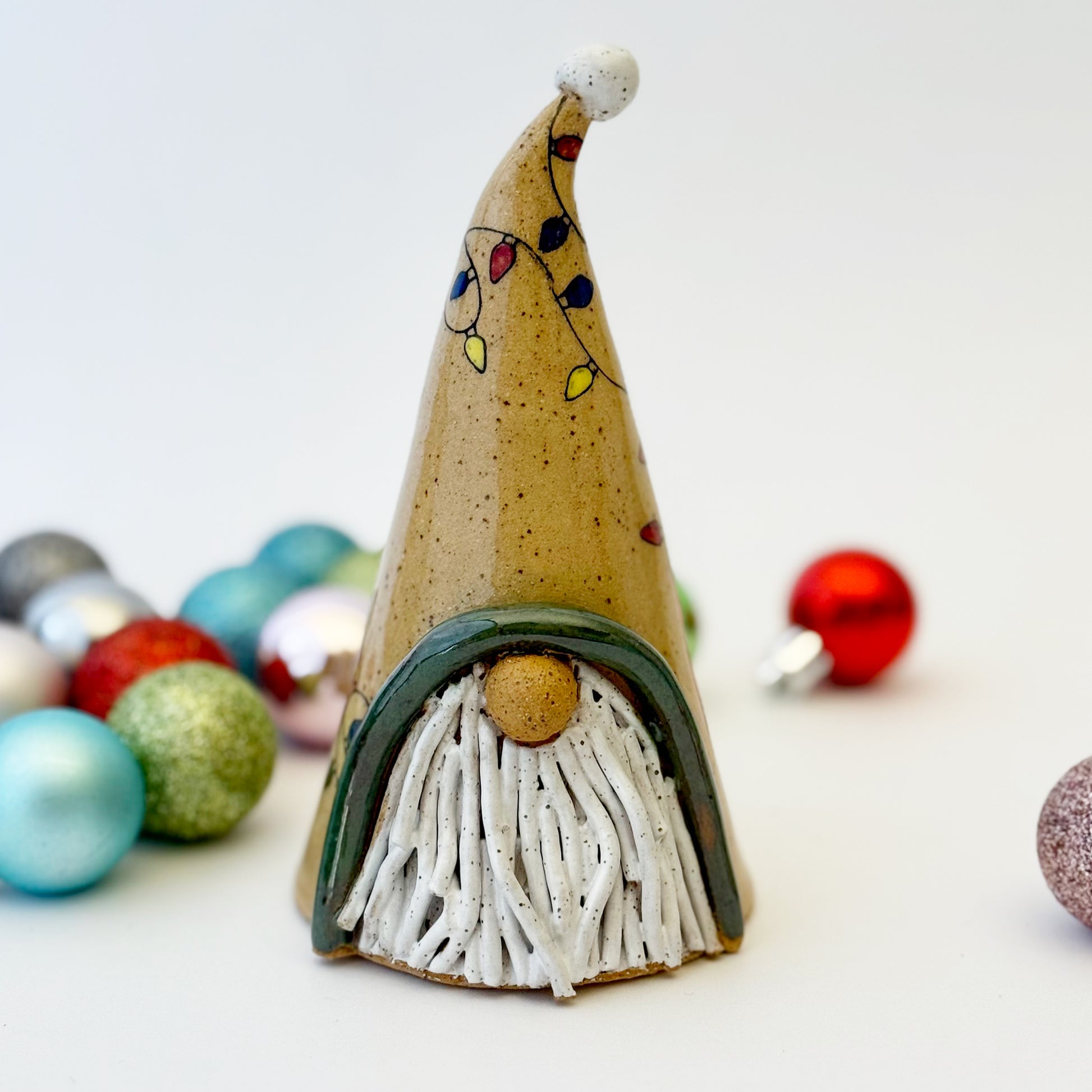 ceramic gnome with holiday lights with ornament on a white background