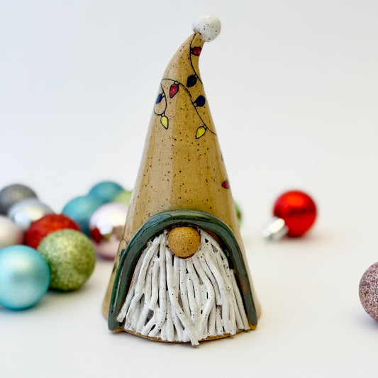 ceramic gnome with holiday lights with ornament on a white background