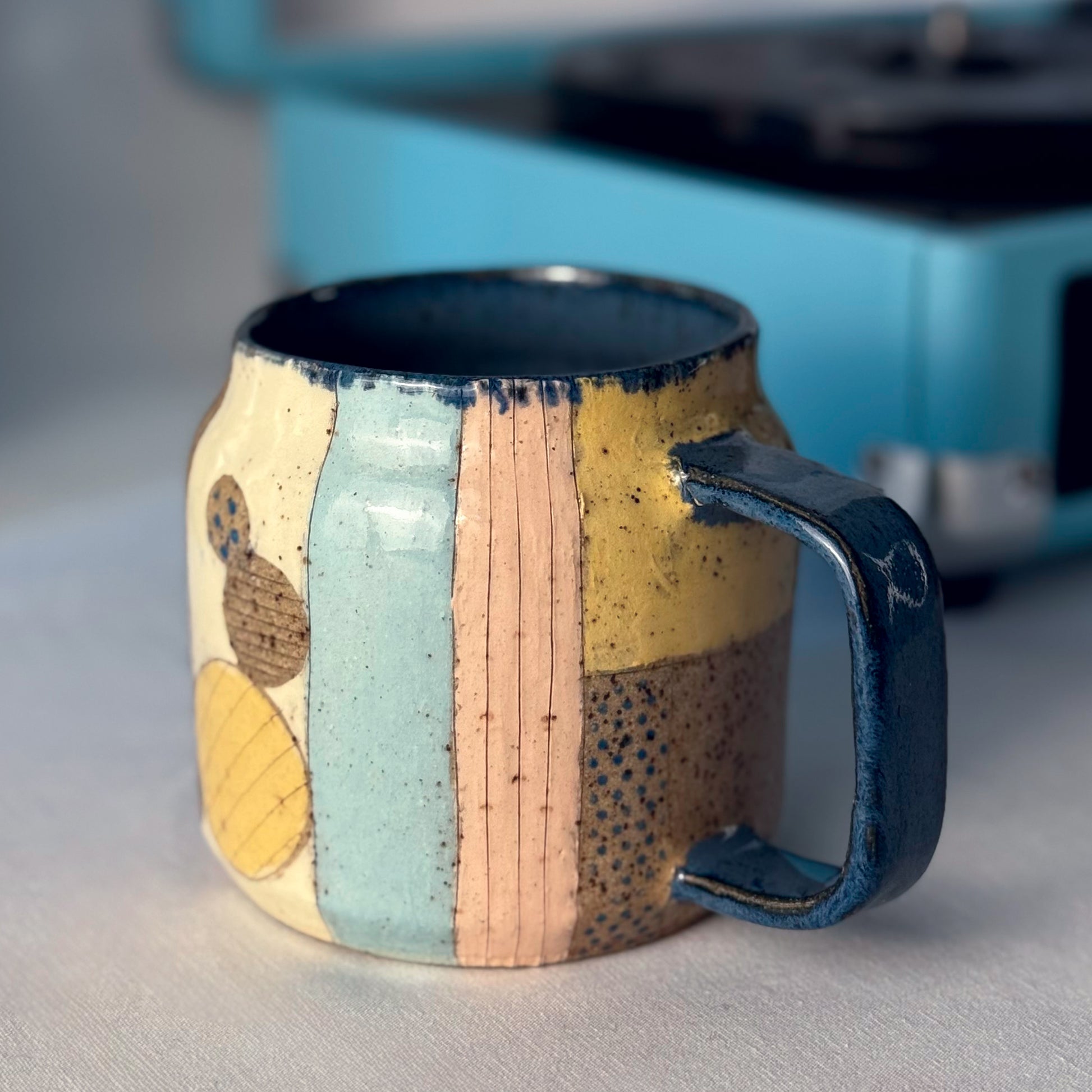Ceramic mug with multicolored pattern on a neutral background