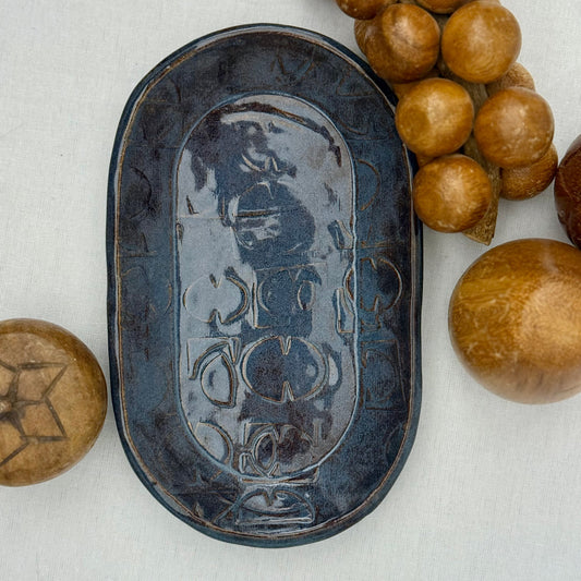 ceramic tray with mid century texture surrounded by monkey pod wooden fruit on a light background